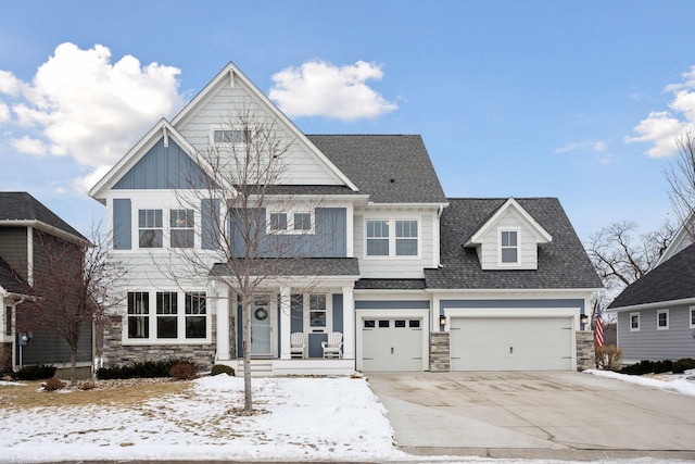 craftsman-style house with board and batten siding, stone siding, driveway, and a shingled roof