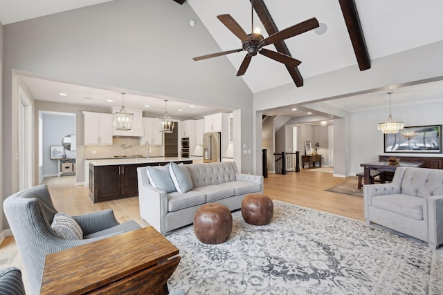 living area with beam ceiling, ceiling fan with notable chandelier, high vaulted ceiling, and light wood-style floors