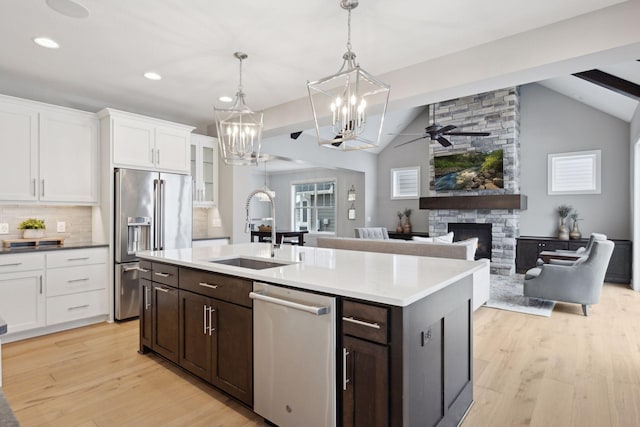 kitchen with light wood-style flooring, a fireplace, a sink, appliances with stainless steel finishes, and white cabinetry