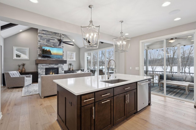 kitchen featuring dark brown cabinets, dishwasher, a stone fireplace, a ceiling fan, and a sink