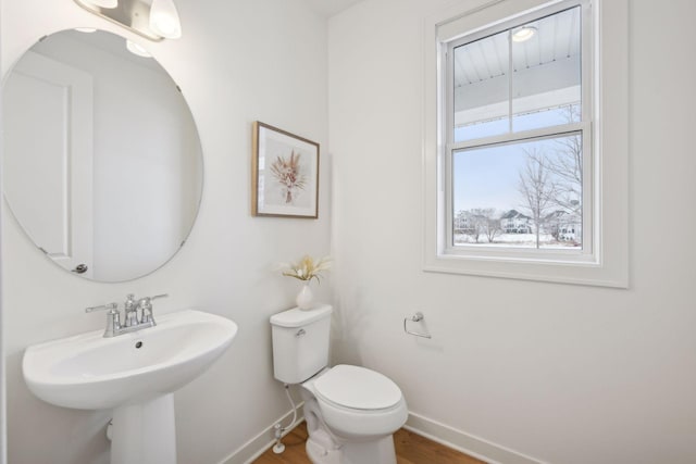 bathroom featuring wood finished floors, toilet, baseboards, and a sink