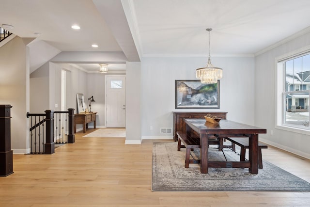 dining space featuring crown molding, light wood-style flooring, a notable chandelier, and baseboards