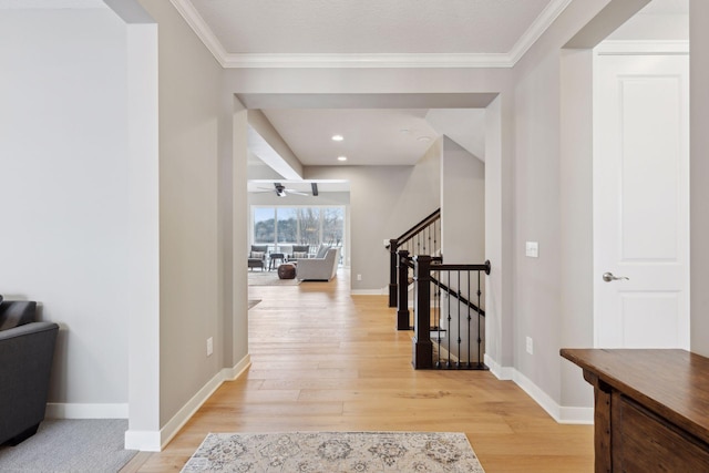 hall featuring stairway, light wood-style flooring, crown molding, and baseboards