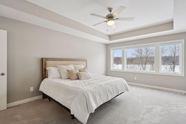 bedroom featuring a ceiling fan, visible vents, baseboards, carpet floors, and a raised ceiling