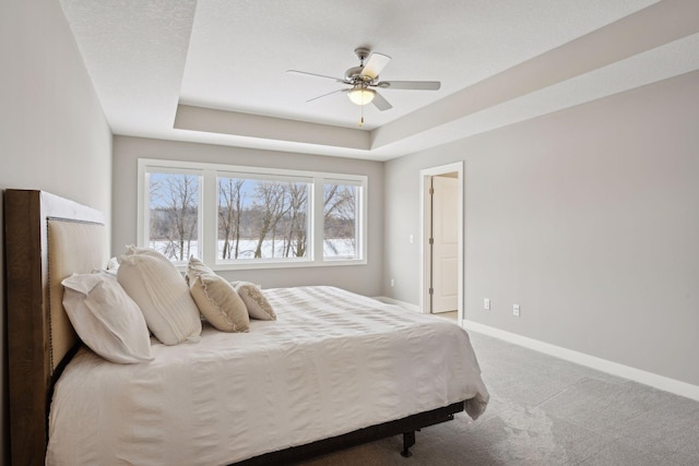 bedroom with ceiling fan, a raised ceiling, baseboards, and carpet floors