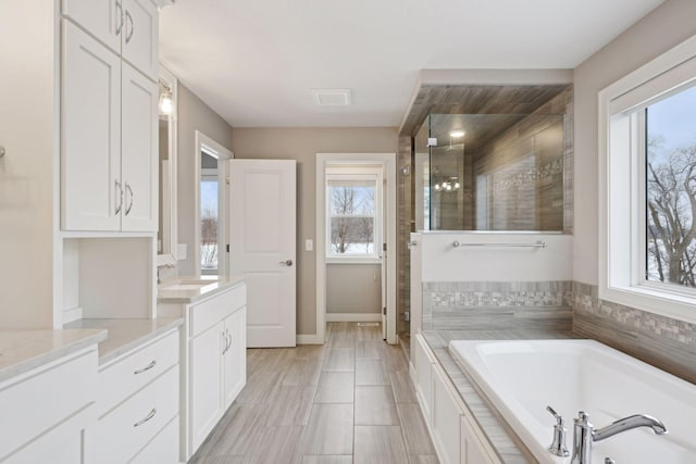 full bathroom with baseboards, vanity, a bath, and a shower stall