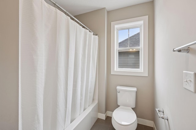 bathroom featuring toilet, shower / tub combo, and baseboards