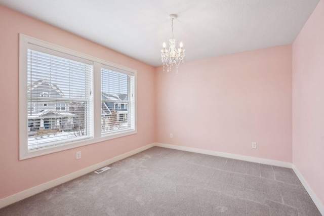 spare room with an inviting chandelier, carpet flooring, visible vents, and baseboards