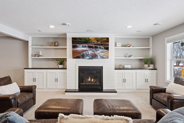 living area with a textured ceiling, a large fireplace, built in features, and light carpet