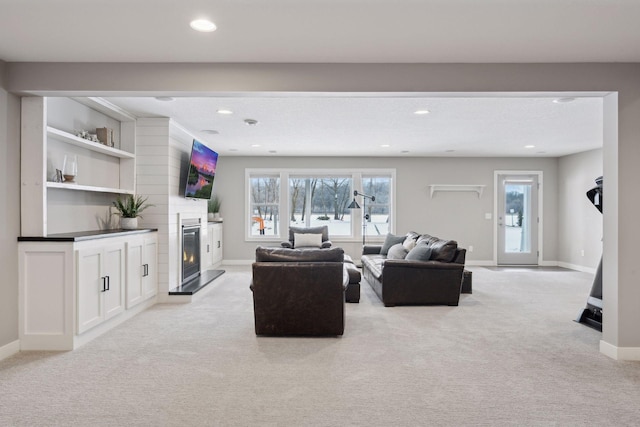 living area with light carpet, a glass covered fireplace, recessed lighting, and baseboards