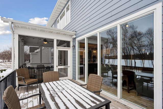 snow covered deck featuring outdoor dining space and a sunroom