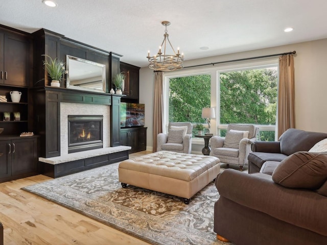 living room with a notable chandelier, light wood-style floors, recessed lighting, and a tile fireplace