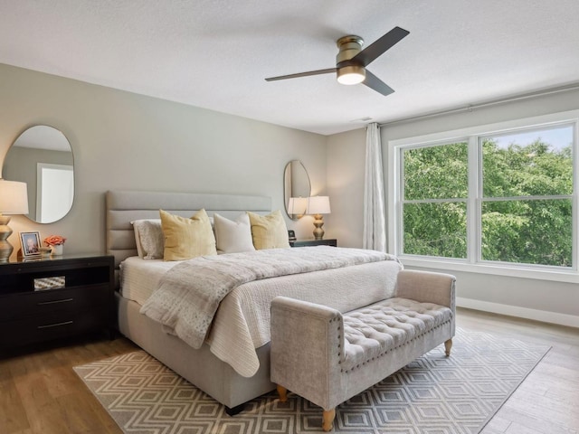 bedroom with wood finished floors, baseboards, and ceiling fan