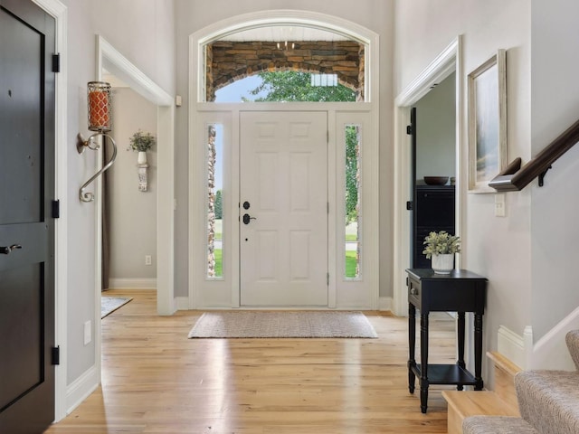 foyer featuring light wood-type flooring, stairs, and baseboards