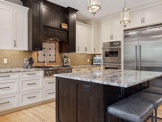 kitchen featuring light stone counters, stainless steel appliances, a kitchen bar, backsplash, and a center island