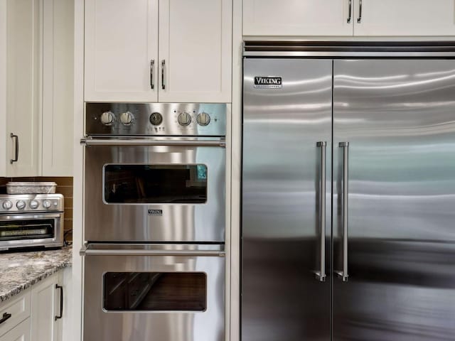 kitchen with white cabinetry, a toaster, light stone counters, and stainless steel appliances