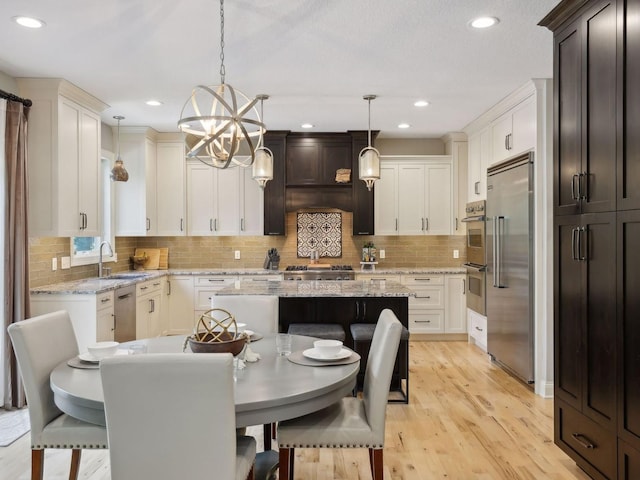 kitchen featuring light stone counters, a kitchen island, light wood-style flooring, a sink, and stainless steel appliances