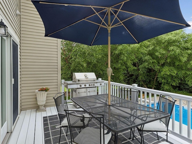 wooden terrace featuring outdoor dining space, an outdoor pool, and grilling area