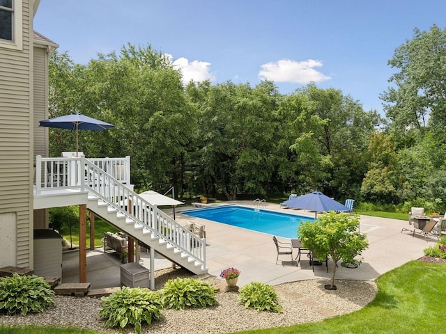 outdoor pool featuring a patio area, a wooden deck, and stairs