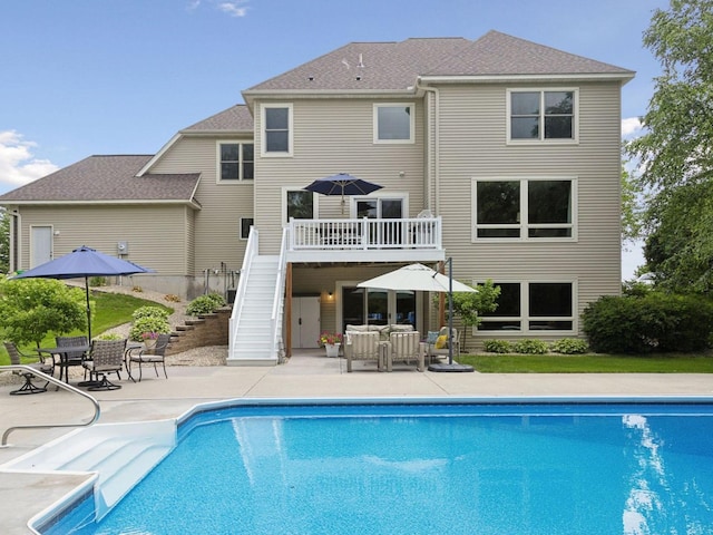 back of house featuring an outdoor pool, a wooden deck, a patio, and stairs