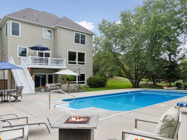 outdoor pool with an outdoor living space with a fire pit, stairway, a deck, a patio, and a diving board