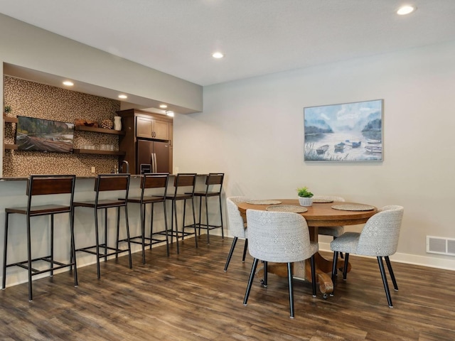 dining room featuring indoor wet bar, recessed lighting, dark wood finished floors, and visible vents