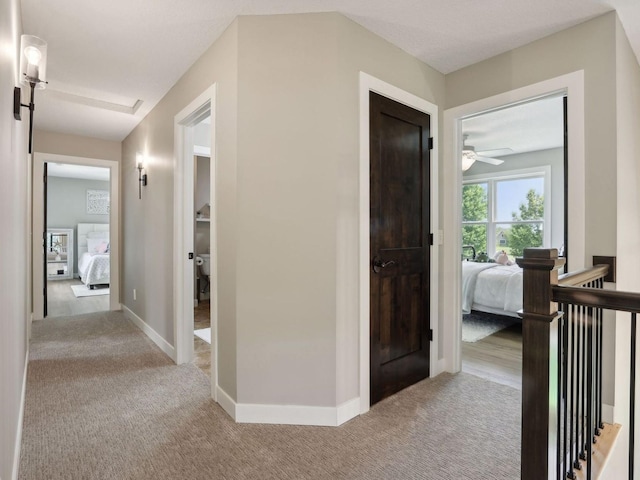 hall featuring an upstairs landing, carpet flooring, and baseboards