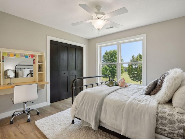 bedroom with light wood finished floors, visible vents, ceiling fan, baseboards, and a closet