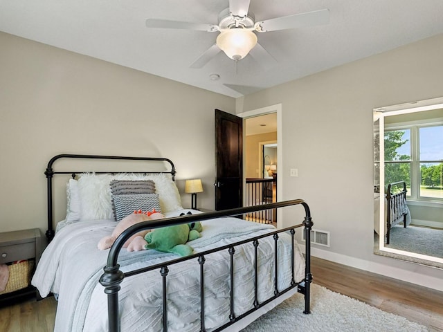 bedroom featuring a ceiling fan, wood finished floors, visible vents, and baseboards