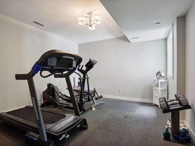 exercise room with visible vents, baseboards, and a textured ceiling