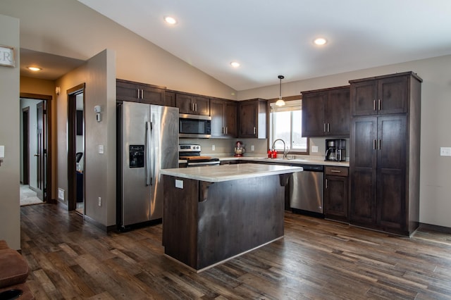 kitchen with sink, vaulted ceiling, a kitchen island, pendant lighting, and stainless steel appliances