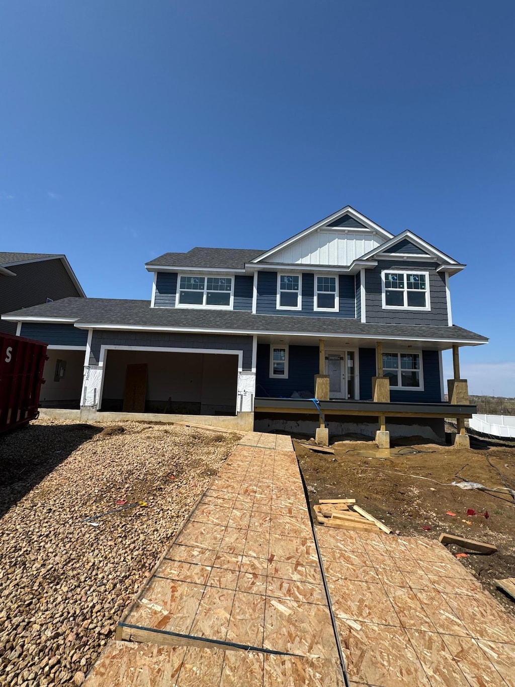 view of front facade with board and batten siding, covered porch, and driveway