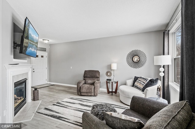 living room featuring light wood-style floors, a textured ceiling, baseboards, and a premium fireplace