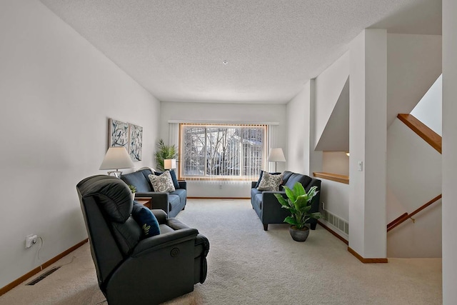 living area featuring light carpet, a textured ceiling, visible vents, and baseboards