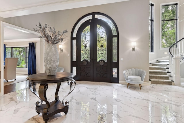 foyer entrance with ornamental molding and french doors