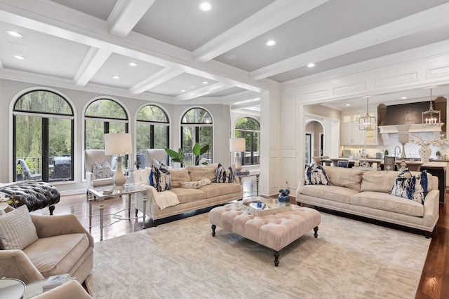 living room featuring coffered ceiling, plenty of natural light, beam ceiling, and light hardwood / wood-style flooring