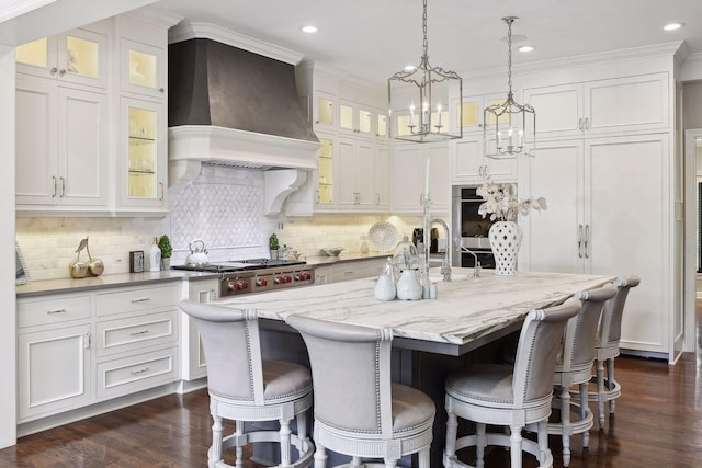 kitchen with white cabinetry, decorative light fixtures, a center island with sink, custom range hood, and stainless steel gas stovetop