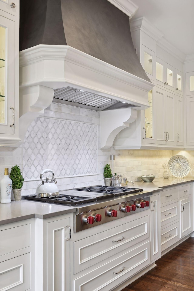 kitchen with decorative backsplash, custom range hood, white cabinets, and stainless steel gas cooktop