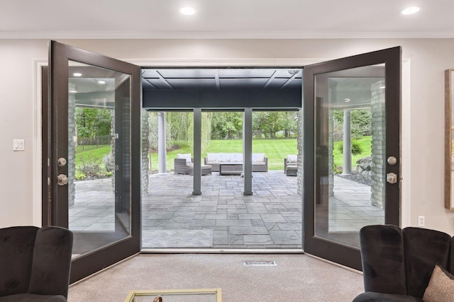 doorway to outside with ornamental molding and light carpet