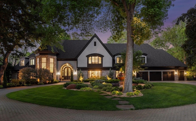 french provincial home with a garage and a lawn