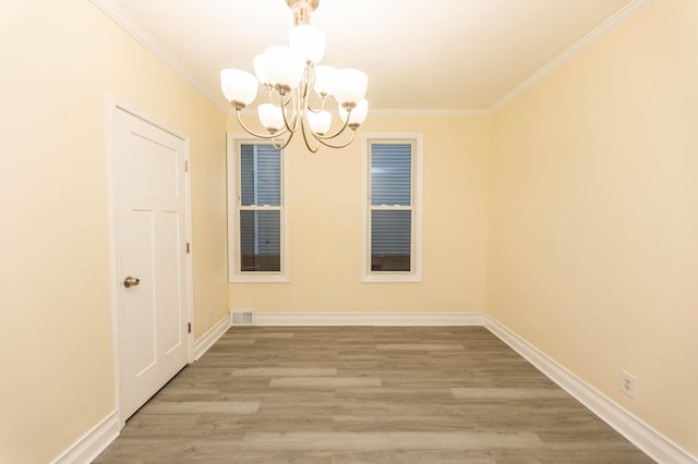 empty room with an inviting chandelier, hardwood / wood-style floors, and ornamental molding