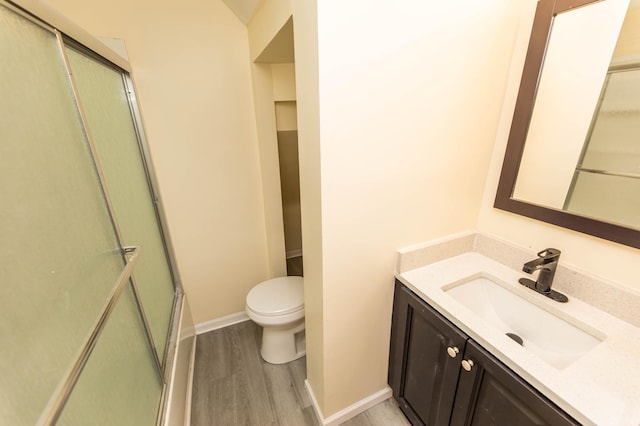 bathroom with vanity, hardwood / wood-style floors, a shower with shower door, and toilet