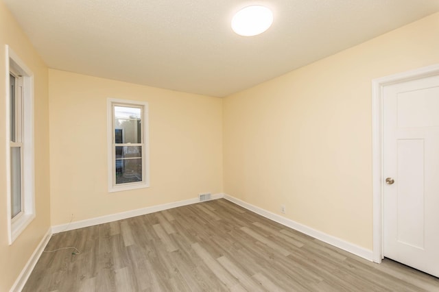 unfurnished room featuring light hardwood / wood-style floors and a textured ceiling