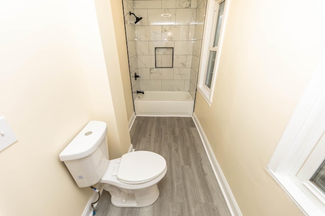 bathroom featuring tiled shower / bath combo, wood-type flooring, and toilet