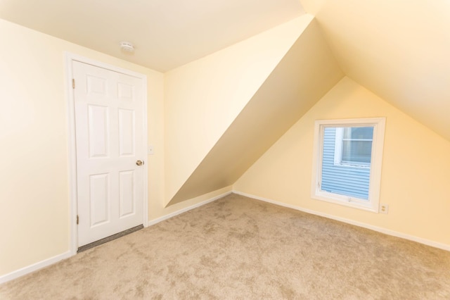 additional living space featuring lofted ceiling and light carpet