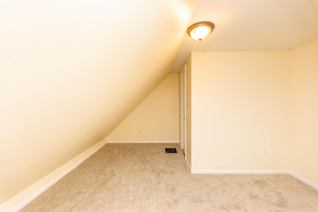 additional living space featuring light colored carpet and lofted ceiling