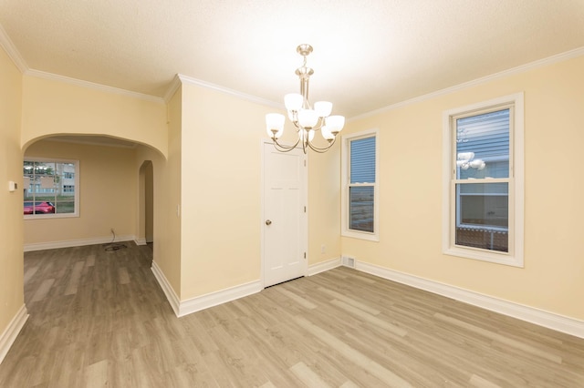 empty room with crown molding, a textured ceiling, a chandelier, and light hardwood / wood-style flooring