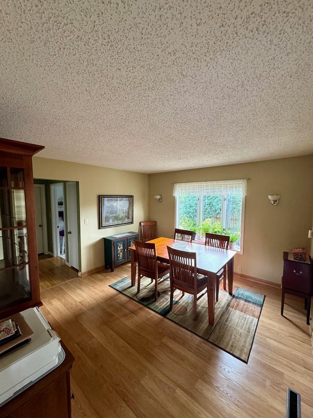 dining room with light hardwood / wood-style flooring and a textured ceiling