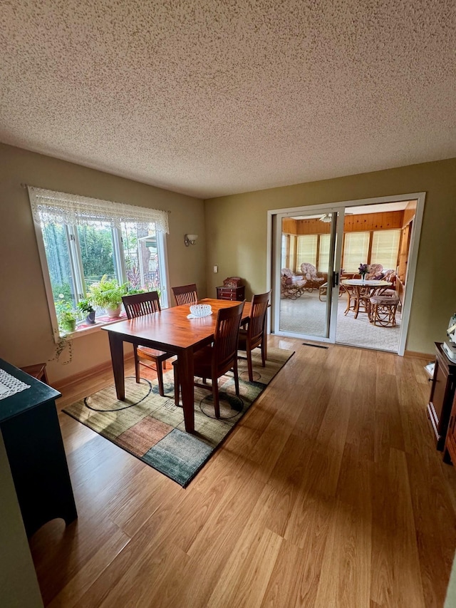 dining space with hardwood / wood-style floors and a textured ceiling