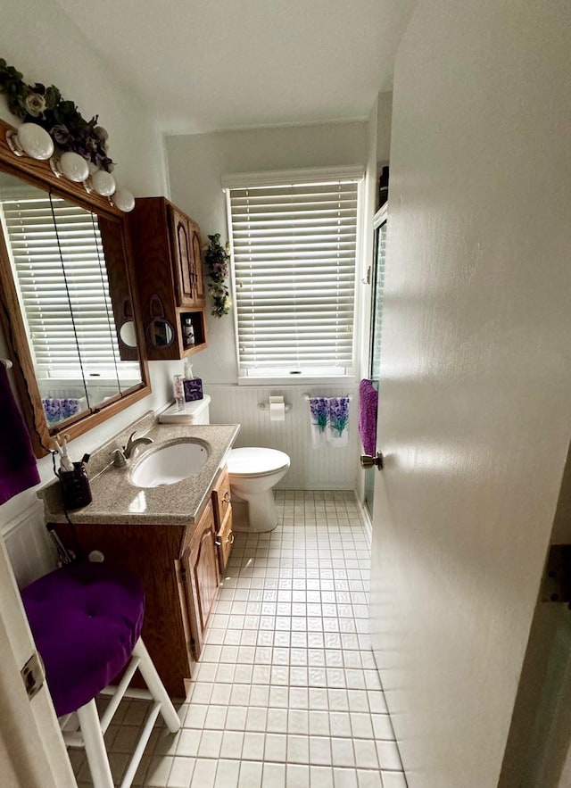 bathroom with vanity, toilet, tile patterned flooring, and a wealth of natural light